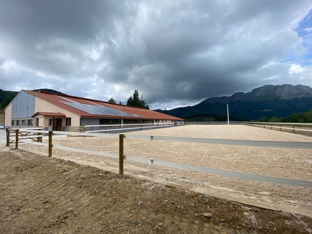 Pista de picadero cerrada con vallado de madera de dos alturas y cinta eléctrica sobre los postes