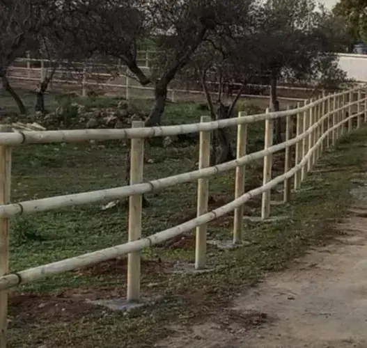 Vallado tejano de madera torneada de tres alturas siguiendo el desnivel del terreno en un olivar